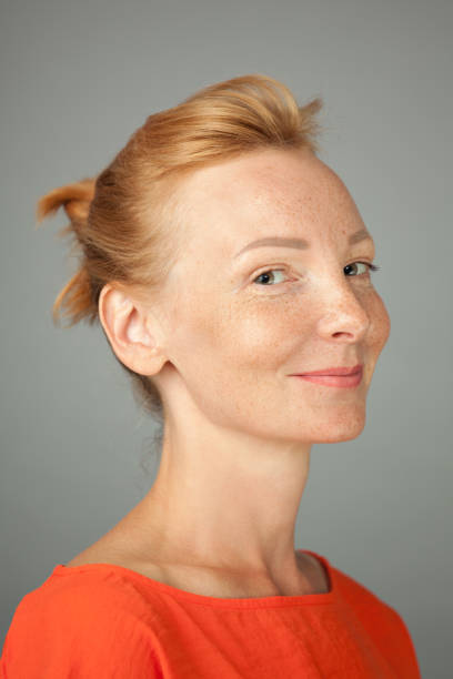 Studio portrait of woman blonde with freckles on gray background Studio portrait of woman blonde with freckles on gray background three quarter view stock pictures, royalty-free photos & images