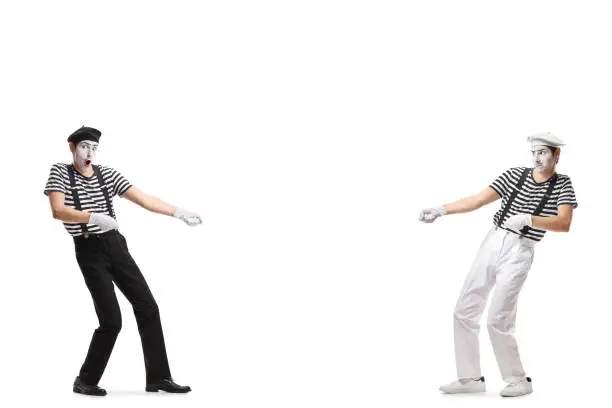 Full length shot of two pantomime men pulling an imaginary rope isolated on white background