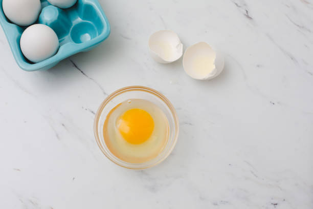istock White Eggs in Tourquoise Egg Tray, One Broken in Clear Bowl, White Marble Countertop 1160289690