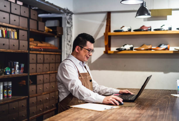 istock Male Taiwanese Shoe Merchant Working on Laptop 1160296988