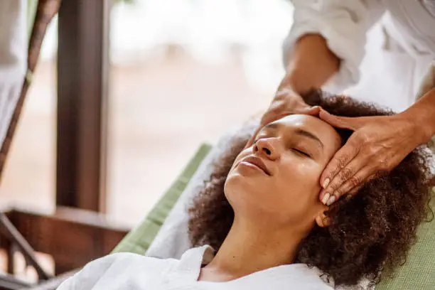 Young mixed race woman enjoying a relaxing head massage at the luxury wellness resort.