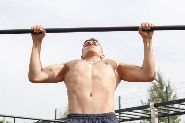 istock Healthy Lifestyle. Young man naked torso doing pull ups on bar outdoors concentrated close-up 1160297080