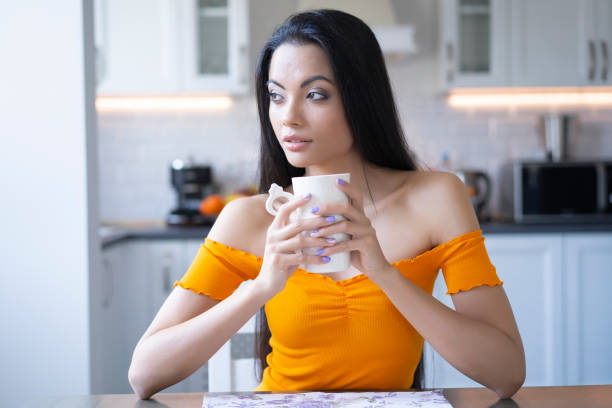 istock Young woman sitting at home and resting, drinking coffee 1160297220