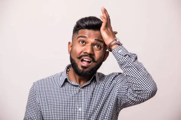 Photo of Annoyed Indian man slapping forehead and blaming himself. Regretful handsome dark haired man wearing denim shirt gesturing and looking at camera. Forgetfulness concept.