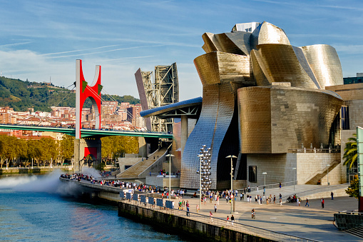 Bilbao, Spain - September 24, 2017: Panoramic view of La Salve Bridge and Guggenheim Museum, designed by ‬Frank Gehry, on the bank of Nervion river. A famous and very popular place for worldwide tourism which has boosted Bilbao's economy with its astounding success. The Guggenheim Museum is a fusion of ‬swirling forms that responds to an intricate program and an industrial and urban context‭.
