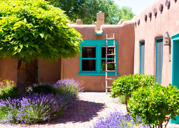 Santa Fe, NM: A traditional old adobe house with sunny interior bricked courtyard with a catalpa tree, bushes, and lavender in summer.