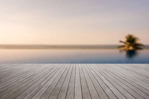 Wooden terrace with tropical infinity pool blurred abstract background