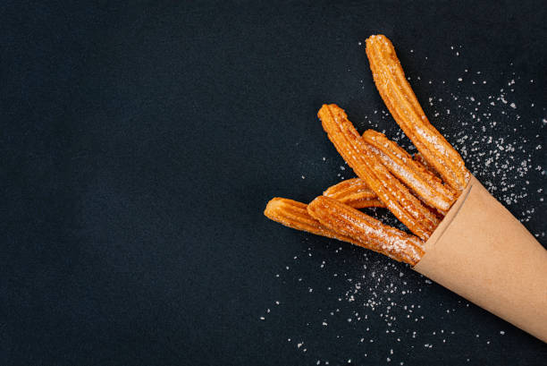 istock Churro on a black background. Traditional Spanish cusine. Churros in a paper bag with copy space. Top view 1160328992