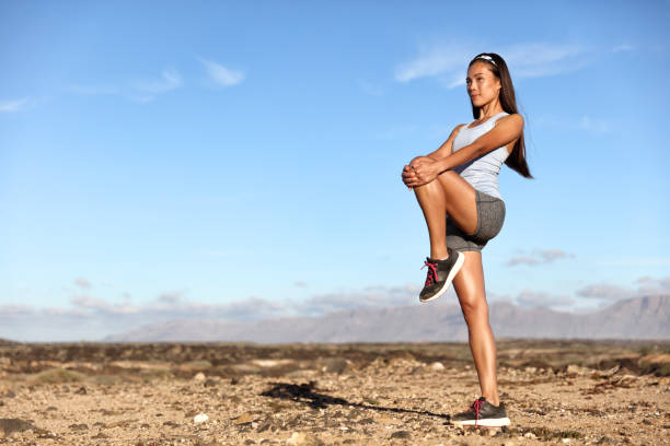 Standing Glutes leg stretch fitness woman workout Standing Gluteus maximus leg stretches. Fitness woman doing stretch exercises workout stretching glutes muscles and hamstring as warm-up for cardio exercise. Trail running in summer outdoor nature. hamstring stock pictures, royalty-free photos & images