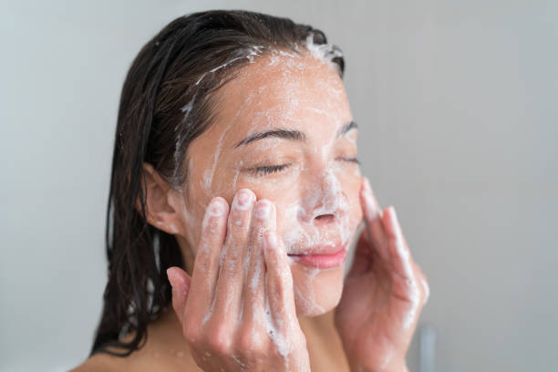 Skincare woman washing face in shower Skincare woman washing face in shower foaming facewash soap scrub on skin. Asian female adult cleaning body showering in hot water at home on in hotel as morning routine. Enjoying relaxing time. exfoliating scrub stock pictures, royalty-free photos & images