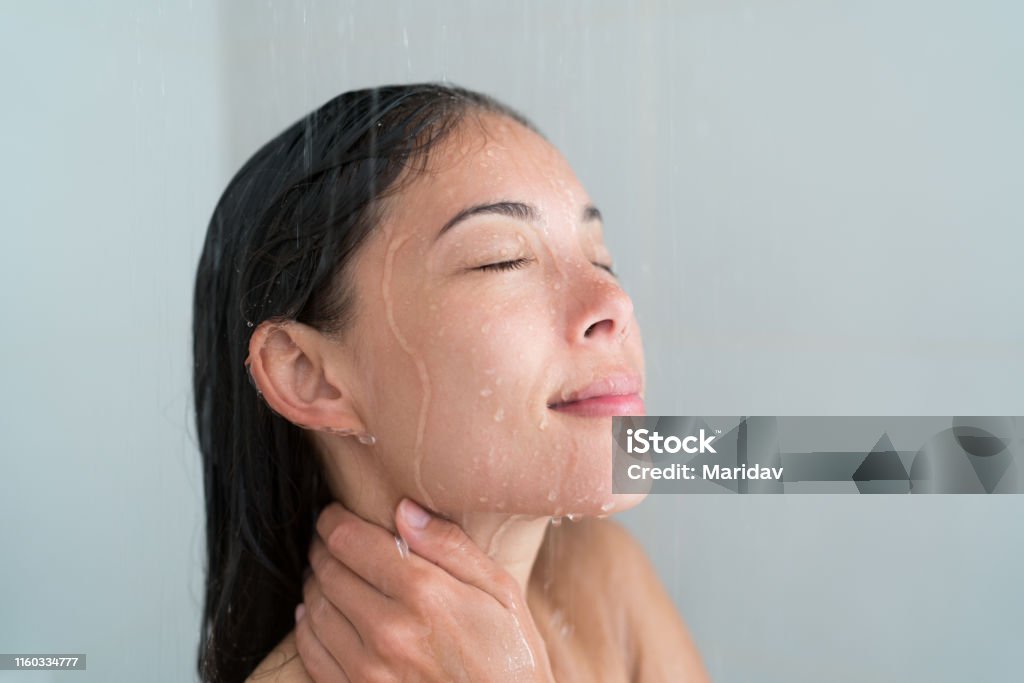Shower woman showering relaxing washing face Shower woman showering relaxing under water massaging neck in hot shower. Asian female adult face enjoying spa relaxation time relaxing meditating in warm bath cleaning face and body at home. Shower Stock Photo