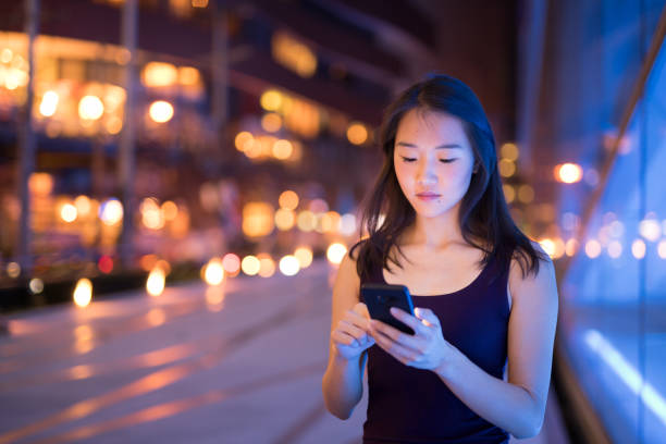 istock Beautiful Asian Woman Outdoors At Night Using Mobile Phone 1160336902