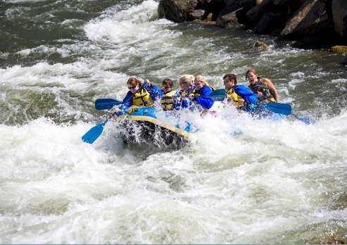 A group of men, women and children, with a guide, white water rafting on the Arkansas River in Colorado.