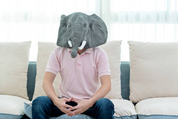 Man wearing a mask sitting on sofa.