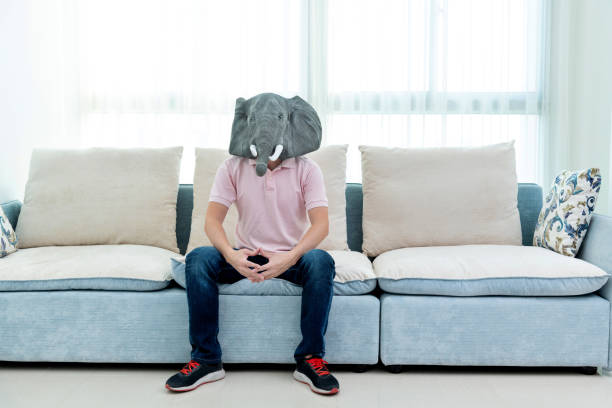 Man wearing a mask sitting on sofa.