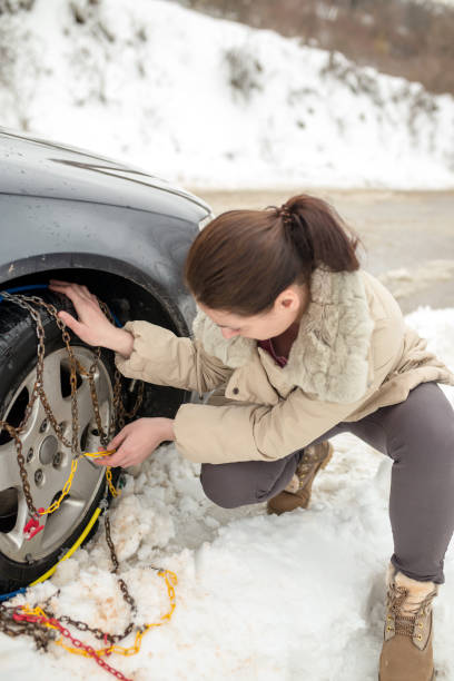 istock Beautiful woman installing snow chain on her car 1160339901