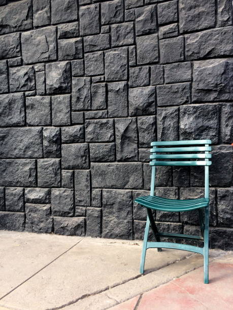 istock Green chair on black stone wall or fence background 1160340848