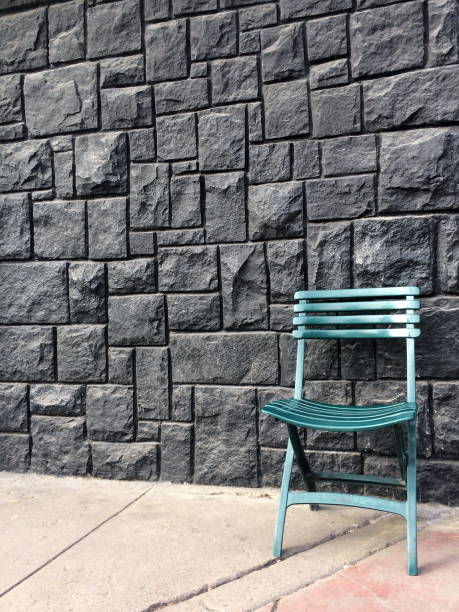istock Green chair on black stone wall or fence background 1160340875