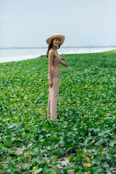 портрет красивой азиатской молодой женщины, стоящей на естественном морском пляже - fashion fashion model asian ethnicity tall стоковые фото и изображения