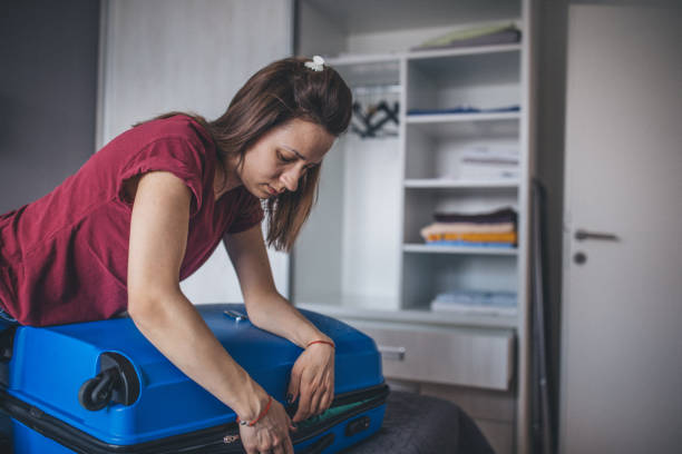 istock Woman closing overpacked suitcase 1160344225