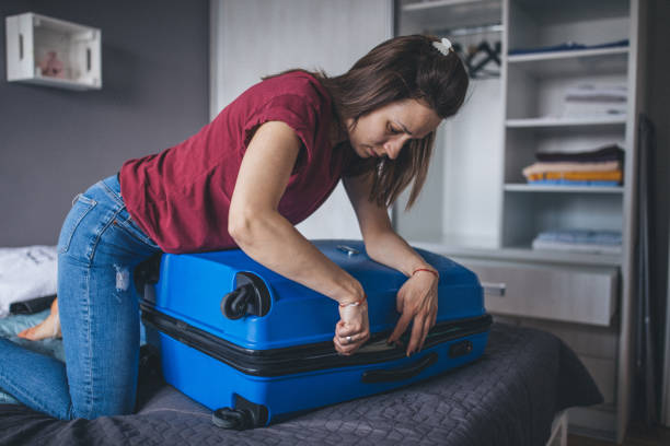 istock Woman in bedroom closing suitcase 1160344259