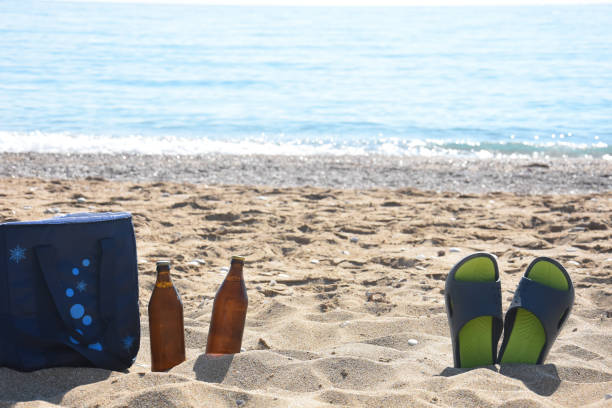 istock Cold beer and slippers on sand at beach 1160345153