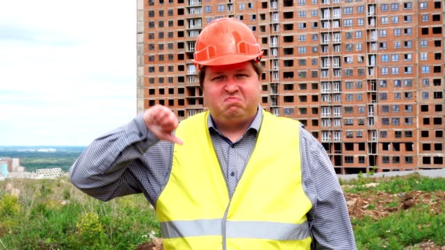 Male builder foreman, worker or architect on construction building site showing thumb down and looking to camera