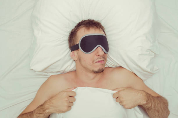 istock Man resting in a mask for sleep. Stubble on his face. Tired man 1160362075