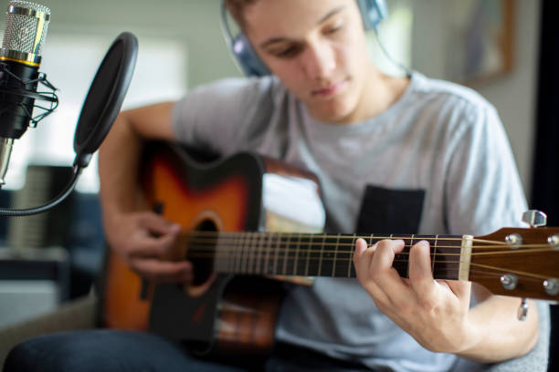 自宅でギターを演奏し、音楽を録音する十代の少年 - home  audio ストックフォトと画像