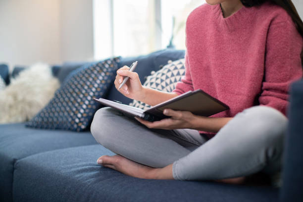 日記に書き込む自宅でソファでリラックス若い女性のクローズアップ - writing equipment 写真 ストックフォトと画像