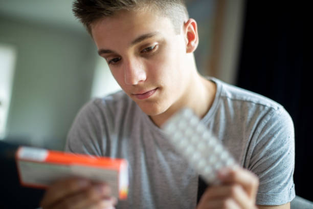 Close Up Of Unhappy And Depressed Teenage Boy At Home Teenage Boy With Mental Health Problems Taking Medication At Home self harm photos stock pictures, royalty-free photos & images