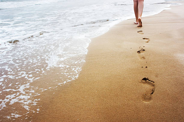 Walking on the sand A young woman walking on the sand. footprint stock pictures, royalty-free photos & images