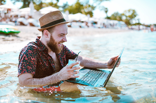 Male Enjoying Videos On His Waterproof Laptop At The Beach