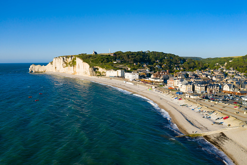 This photo was taken in France, north of Normandy, in Etretat. You can see the city, the pebble beach and the dike. You can see the cliffs in the background.