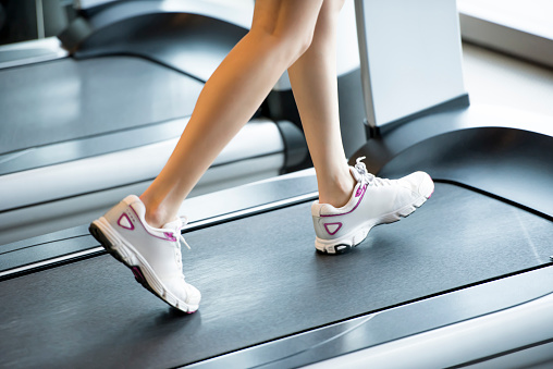 Close up photo of female legs walking on the treadmill in the gym, selective focus