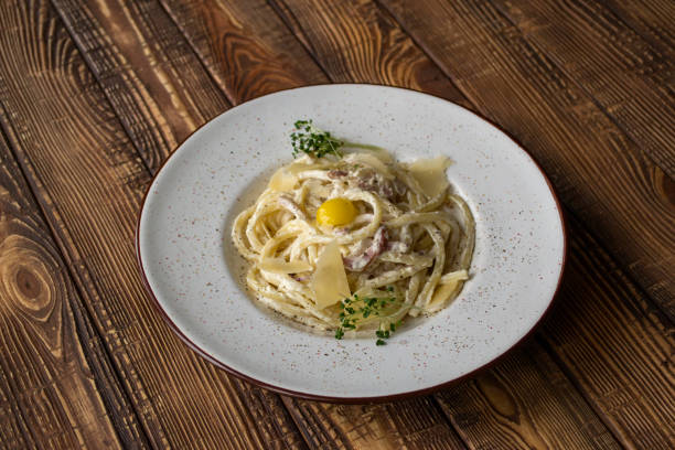 istock Pasta with parmesan, basil, and bacon on a wooden table. Pasta carbonara. 1160379099