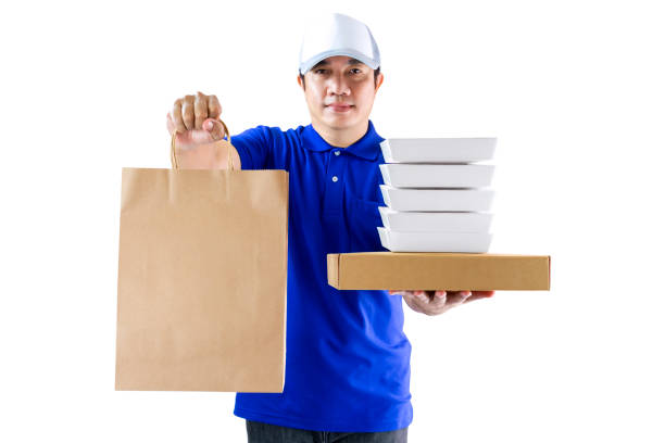 servizio di consegna di cibo o ordinare cibo online. fattorino in uniforme blu che tiene il contenitore per imballaggi alimentari e un sacchetto di carta isolato sullo sfondo bianco. (con percorso di ritaglio) - pizza one person service human hand foto e immagini stock