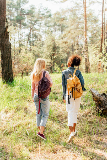 istock back view of two multiethnic friends with backpacks walking in forest 1160382820