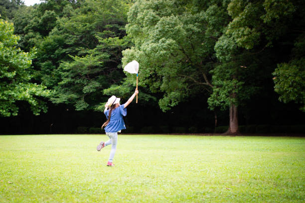 Young multiethnic sibling boy and girl playing together running in park with a colorful pinwheel on sunny day, Happy kids enjoy carefree childhood playtime, healthy energy kids with outdoor activities