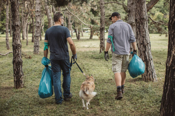 Father and son collecting garbage from park, environmental awareness is important to save our planet. Pet dog is with them too