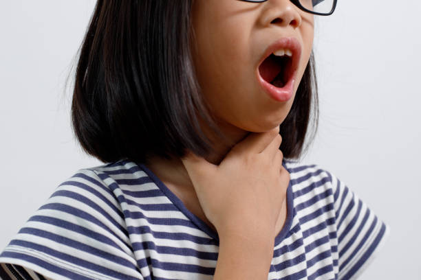 Little Asian girl holding her neck in pain, Sore Throat. stock photo