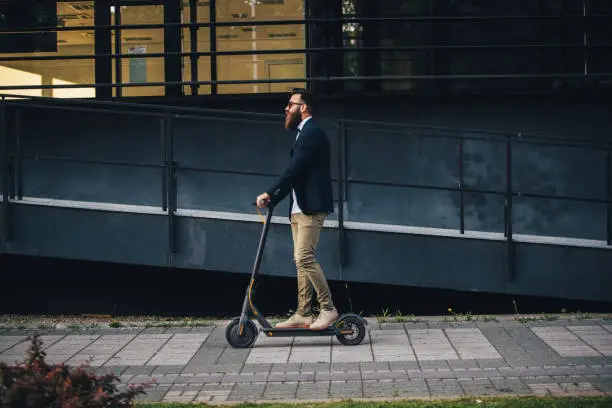 Photo of Hipster riding a scooter in the city