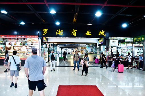 Tourists and shoppers window shopping and browsing through street market shops. Located at North Huaqiang Commercial Area district of Shenzhen - China, many of the shops sell counterfeit goods at knockdown prices.