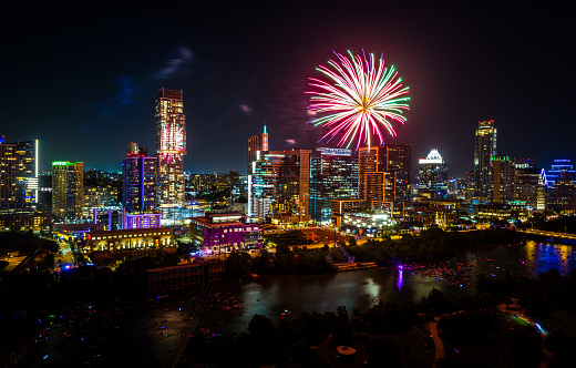 Independence Day , memorial day , or the 4th of July Fireworks Display over Austin , Texas , USA crowds of people watch the fireworks burst into colors high into the air above the Amazing Cityscape Downtown Skyline over Lady Bird Lake