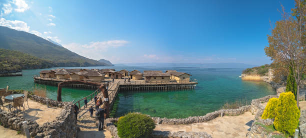 Ohrid, Northern Macedonia -  April 2019 : Panoramic view of the wooden pier leading to the Bay of the bones Museum on water, authentic reconstruction of the pile dwelling settlement