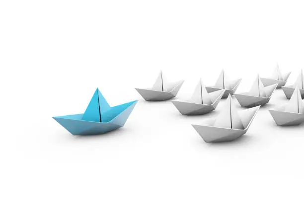 Leadership concept with blue paper ship leading among white