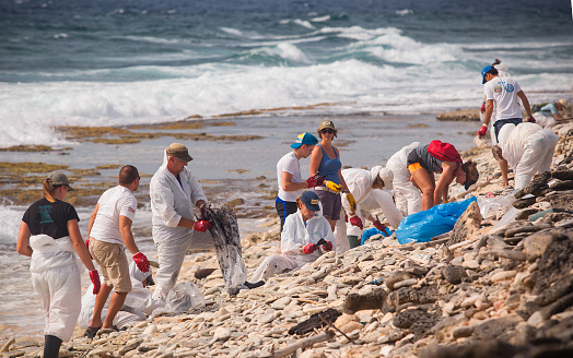 Bonaire 05-07-2019: volunteers cleaning up the oilpatches which has washed up ashore after flooting around in the ocean
