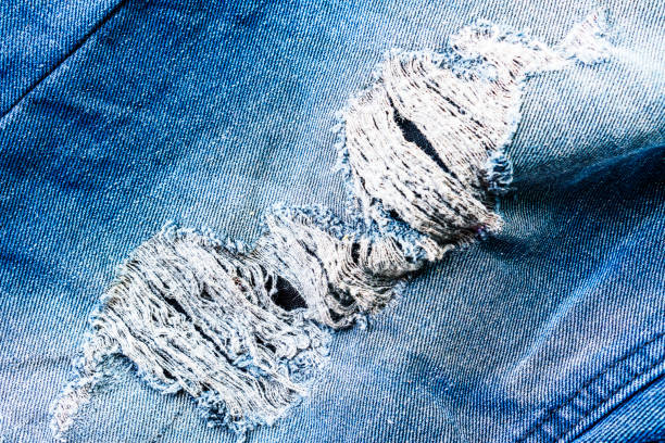 istock Blue jeans of ripped edges torn background - Torn old blue jeans background 1160397156