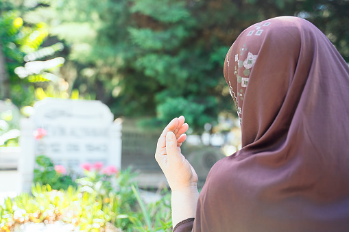 Muslim woman praying in cemetery - Rear view