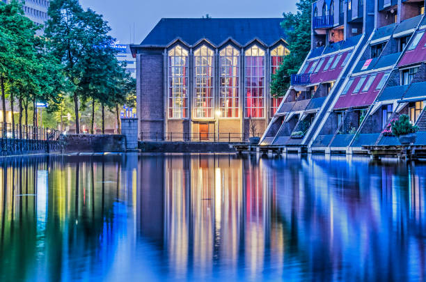 Rotterdam, The Netherlands, May 20, 2019: post-war Baptist church and 1980's housing reflect in the water of Delftsevaart canal during the blue hour